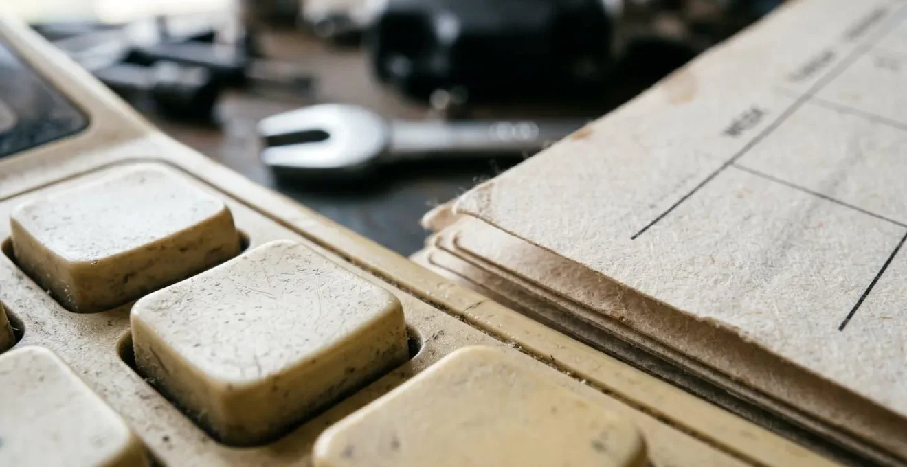 Calculatrice vintage et calendrier avec pièces automobiles en arrière-plan flou