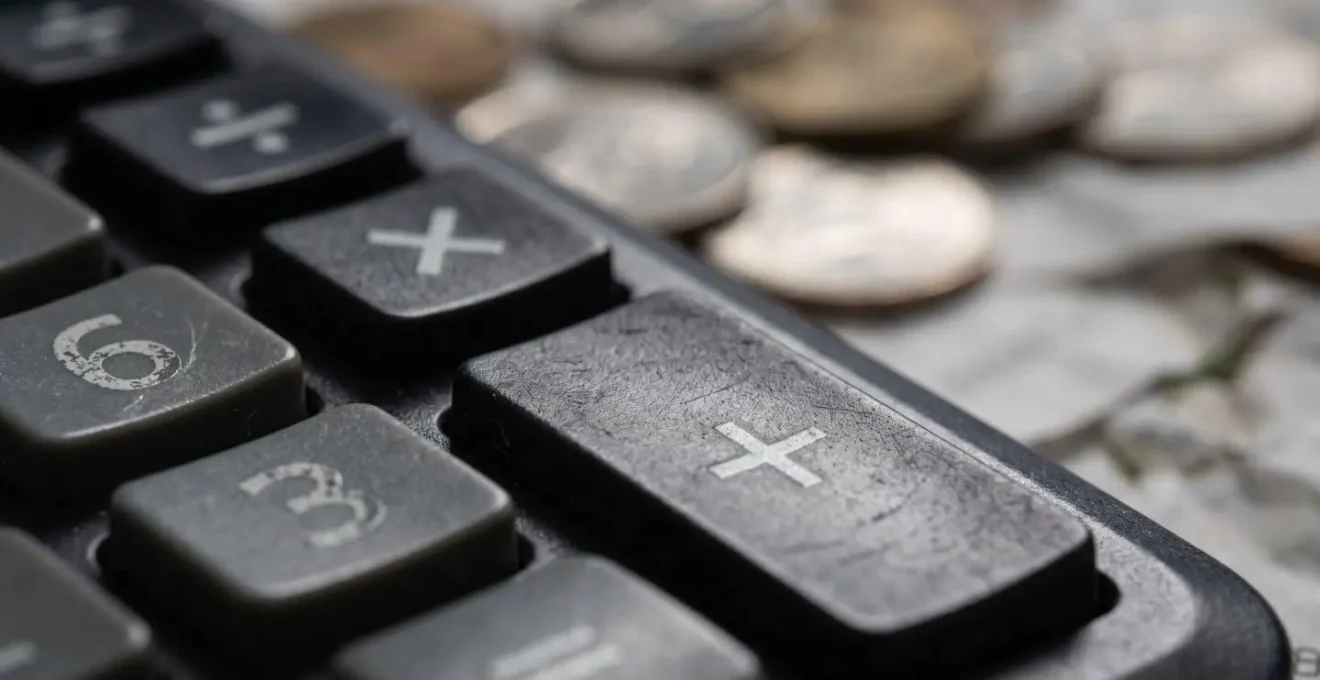 Vue macro d'une calculatrice avec des pièces de monnaie et un ticket de station-service flous en arrière-plan
